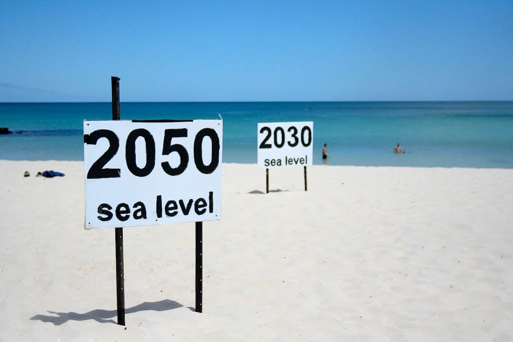 Signs on a beach showing where seal level will be in the years 2030 and 2050